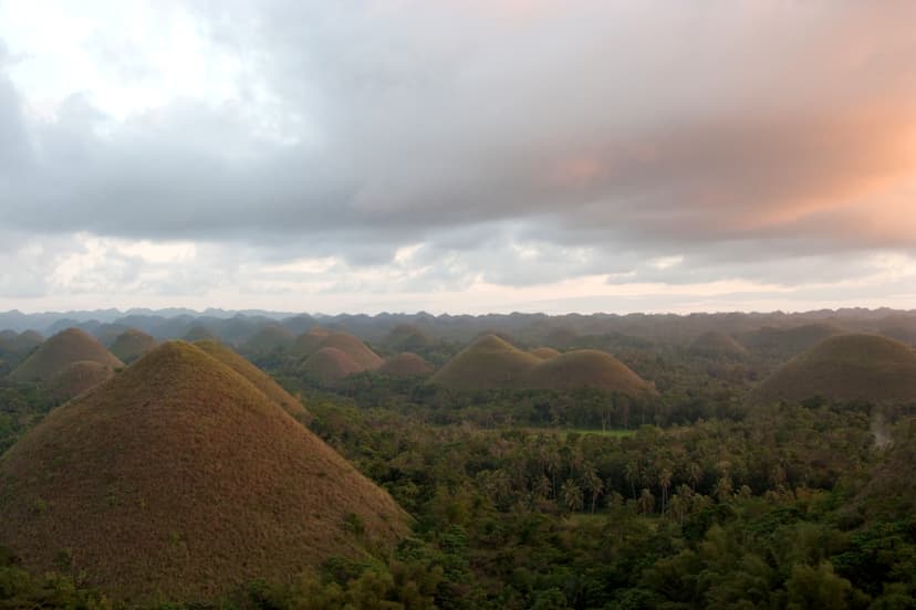 Chocolate Hills au coucher du soleil sous un ciel nuageux rosé, Bohol