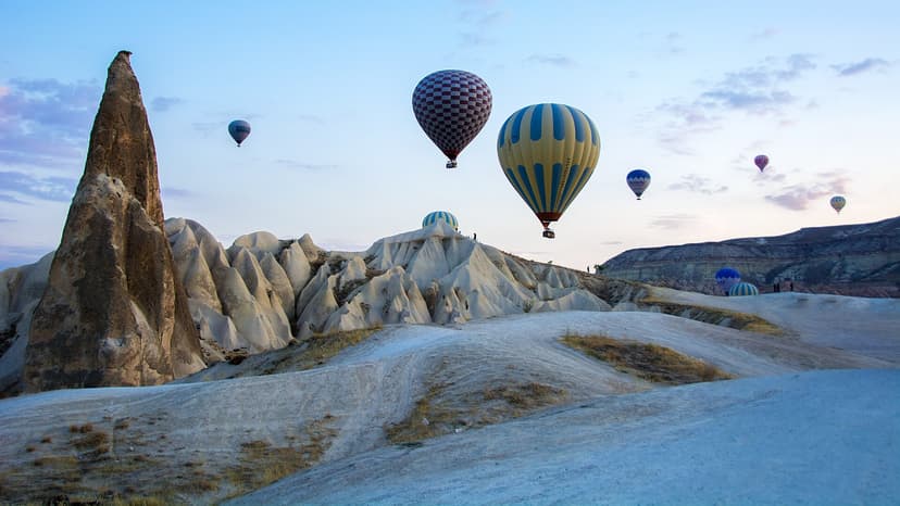 Montgolfières frôlant les crêtes de tuf blanc à l'aube, parc national de Göreme en Cappadoce