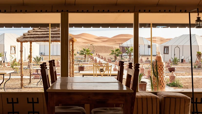 White tents and dining room of a luxury desert camp facing the Erg Chebbi dunes