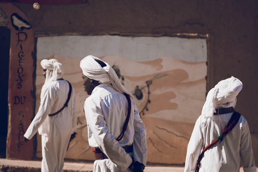 Gnawa musicians in white robes outside a painted house in Khamlia village, near Merzouga