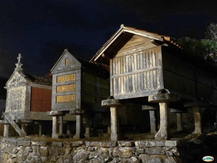 Three granite hórreos lit up at night in Combarro, Rías Baixas
