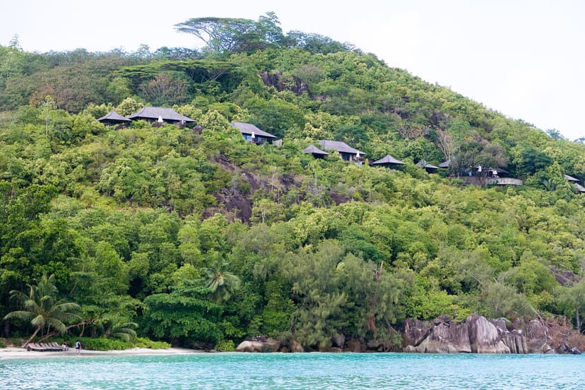 Wooded hillside and granite rocks at the water's edge in Port Launay, west coast of Mahé